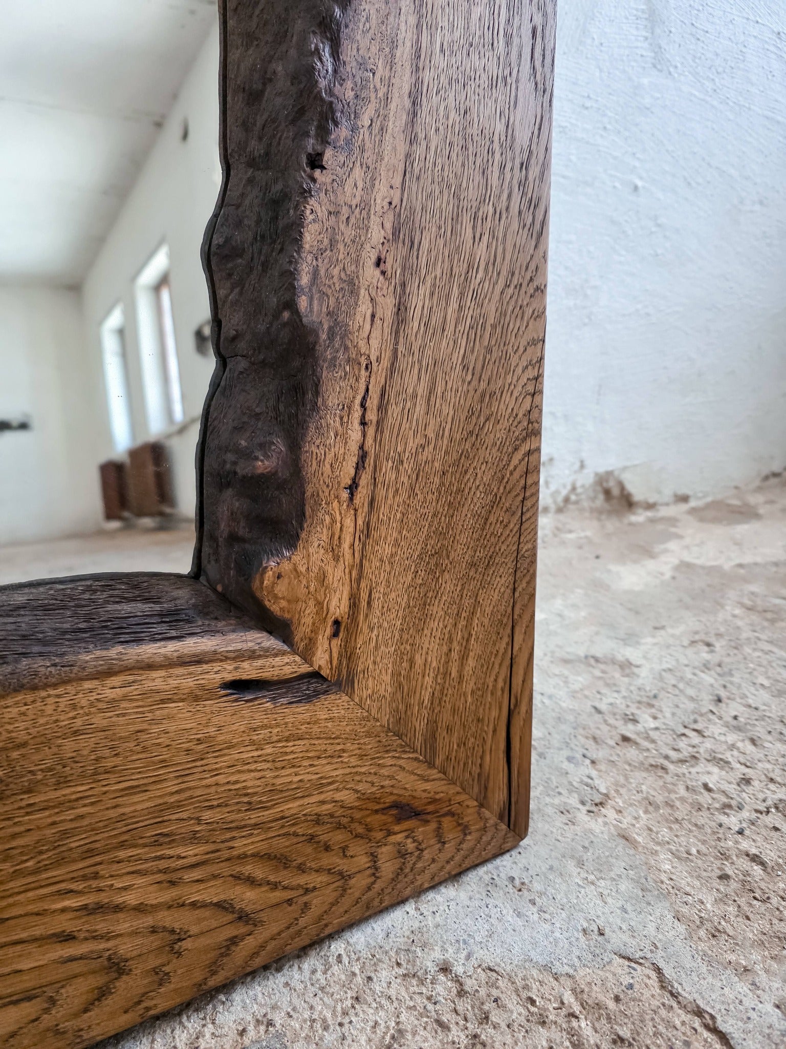 Close-up of a wooden frame corner with a rustic finish on a concrete floor.
